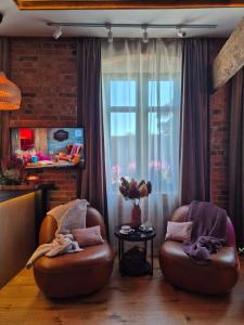 a living room with two chairs and a window at Apartament Przy Murach in Toruń