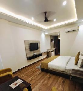 a bedroom with a bed and a flat screen tv at Ganges Blossom Hotel Haridwar in Haridwār +11 photos