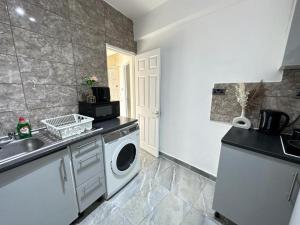 a kitchen with a washing machine and a sink at Edgware Road Beautiful Family Apartment in London