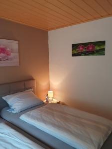 a bedroom with a bed with a lamp and flowers on the wall at Wünschel Stube in Gossersweiler-Stein
