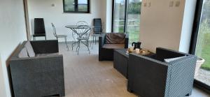 salon z 2 wiklinowymi krzesłami i stołem w obiekcie Villa Maëlla - 2 gîtes - jardin, piscine et SPA privés w mieście Saint-Michel-Tubœuf