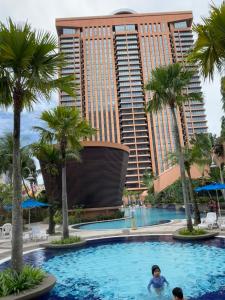 a pool at the resort with palm trees and a tall building at Times Square Hotel Service Apartment At Kl in Kuala Lumpur
