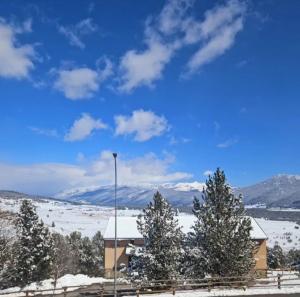 ein schneebedecktes Feld mit Bäumen und einem Gebäude in der Unterkunft Le duplex in Les Angles