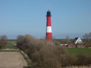 un faro rosso e bianco in mezzo a un campo di Nice Holidays a Pellworm