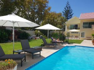 a pool with chairs and umbrellas next to a house at Junior-Suite Merlot in Cape Town
