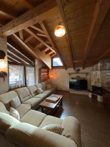 Una gran sala de estar con sofás y un televisor. en Quadrilocale Dolomiti, en Madonna di Campiglio