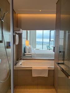 a bathroom with a tub and a bed and a window at Happy home happy sunrise and sunset in Ha Long