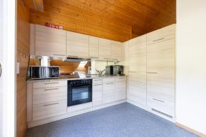 a kitchen with white cabinets and a wooden ceiling at Zentrale Ferieneohnung in Grindelwald in Grindelwald +10 photos
