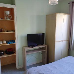 una camera da letto con TV su un tavolo con un letto di studio au calme sur jardin a Saint-Sulpice-de-Royan