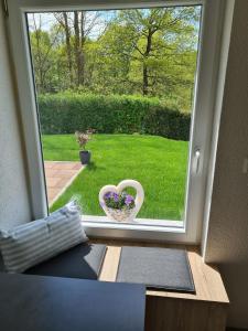 Una ventana con un jarrón con flores. en Gästehaus Waldliebe, 