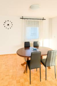 une table à manger avec des chaises et une horloge murale dans l'établissement Apartman Centar Banja Luka, à Banja Luka