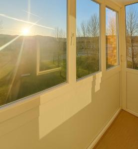 une pièce avec des fenêtres à travers lesquelles le soleil brille dans l'établissement Apartman Centar Banja Luka, à Banja Luka