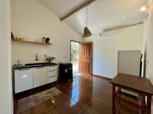 a kitchen with white cabinets and a wooden floor at Casa Sol e mar in Porto Seguro