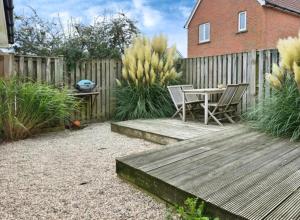 a wooden deck with a table and chairs in a backyard at Rock Lobster in Camber