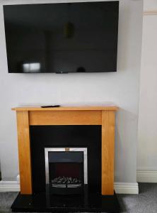a fireplace with a flat screen tv above it at Oge's House in Bradford +7 photos