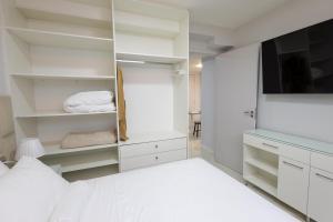 a white bedroom with a bed and a television at Studio Praia do jardim 1 208B in Angra dos Reis
