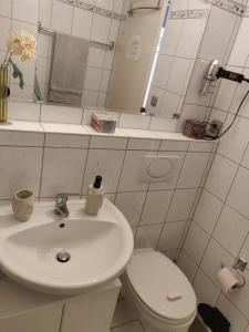 ミュンヘンにあるSchönes, zentral gelegenes Zimmer mit Südbalkonの白い洗面台とトイレのあるバスルーム +12枚の写真