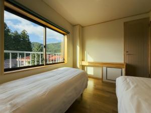ein Zimmer mit zwei Betten und einem großen Fenster in der Unterkunft Schanze Nozawa in Nozawa Onsen