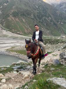 un hombre está montando un caballo en una montaña en Tajiro Homestay, en Taxkorgan