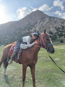 Una mujer montada en la espalda de un caballo marrón en Tajiro Homestay, en Taxkorgan