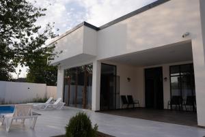 a white house with glass doors and a patio at Villa Mukhrani in Mukhrani