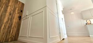 a hallway with white cabinets and a wooden door at Cosy Studio Gdynia Kamienna Góra in Gdynia