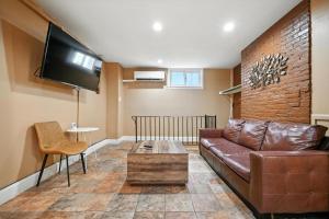 un soggiorno con divano in pelle marrone e TV di Charming Home in Vibrant Philadelphia a Philadelphia
