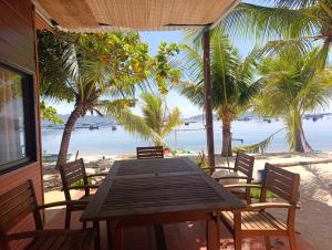 a wooden table and chairs on a beach with palm trees at The Sunrise Anh Tu in Cam Ranh