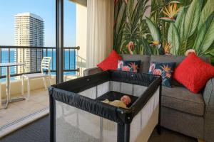 a baby laying in a crib in front of a couch at Top Ocean View Artistic Apt in Gold Coast