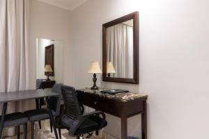 فندق اكارم الصفا Akarem Hotel في جدة: غرفة مع مكتب وكراسي ومرآة