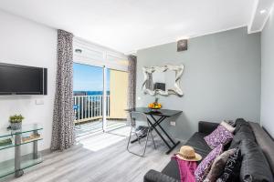 a living room with a couch and a tv and a balcony at Beach apartment in Las Americas in Arona