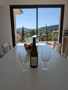 Una botella de vino sobre una mesa con dos copas de vino. en L'échappée Bourguignonne, en La Vineuse