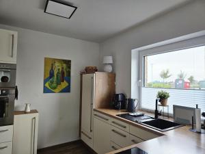 a kitchen with a refrigerator and a window at Wangermeerglück in Wangerland