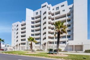 a white building with palm trees in front of it at Mountain Tide in Cape Town