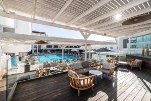 an outdoor deck with a pool and tables and chairs at EVE Eilat by Adam Hotels in Eilat