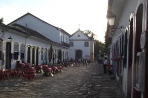 a group of people walking down a street with tables and chairs at Suites Matriz Centro Histórico in Paraty