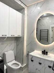 a white bathroom with a toilet and a mirror at Жилой комплекс Космос in Bishkek