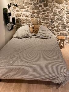 a bed in a room with a stone wall at Maison deux chambres avec grand jardin in Grésy-sur-Aix