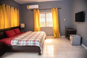 a bedroom with a bed and a window with yellow curtains at Rapid City Guest House Accra in Oshiyie