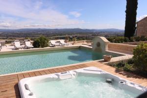 a bath tub sitting on a deck next to a swimming pool at Domaine Jourdan in Le Puy-Sainte-Réparade