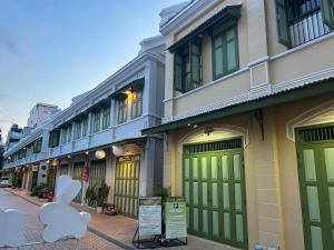 a row of buildings with green doors on a street at Baan Lek Tee 6 - Chinatown near Yaowarat and MRT in Bangkok