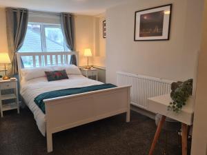 a bedroom with a white bed and a window at Cosy Townhouse Within Caernarfon's Old Town Walls in Caernarfon