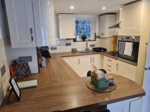 a kitchen with white cabinets and a wooden counter top at Cosy Townhouse Within Caernarfon's Old Town Walls in Caernarfon