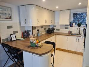 a kitchen with white cabinets and a wooden counter top at Cosy Townhouse Within Caernarfon's Old Town Walls in Caernarfon