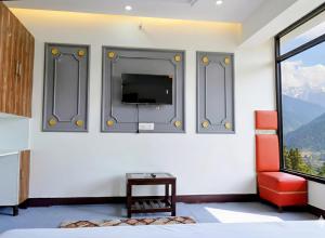 a bedroom with a flat screen tv on a wall at Quiet Edge Resort A Luxury Room With Balcony By Anvi Retreat in Nainital