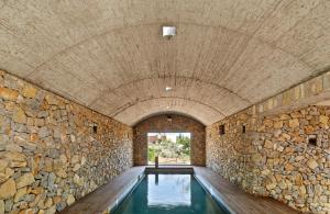 an indoor swimming pool with a stone wall at Son Gener Hotel Spa in Son Servera