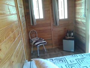 a room with a chair and a table with bottles of wine at Pousada Caverna Rio dos Bugres in Urubici