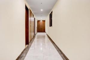an empty corridor with white walls and wooden doors at Hotel O Ginger Gold in Lohogaon
