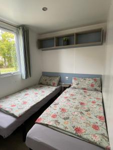 a bedroom with two beds and a window at Nordseechalet direkt am Lauwersmeer - Fußläufig zur Nordsee! Siblu Lauwersoog! Familienpark in Lauwersoog