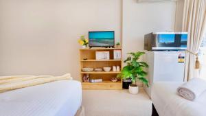 a room with two beds and a refrigerator and a tv at Studio Bliss by the Sea in Gold Coast